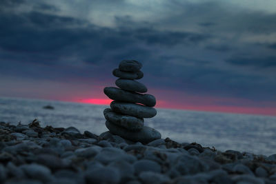 Stack of stones on beach against sky during sunset