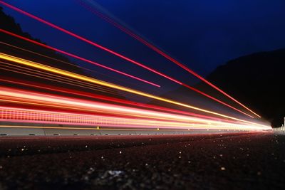 Light trails on road against sky at night