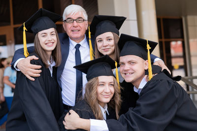 Portrait of smiling friends wearing graduation