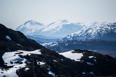 Scenic view of snow covered mountains against cloudy sky