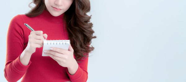 Midsection of woman holding hands against white background