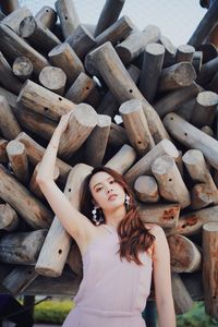 Beautiful woman leaning against stack of wooden log