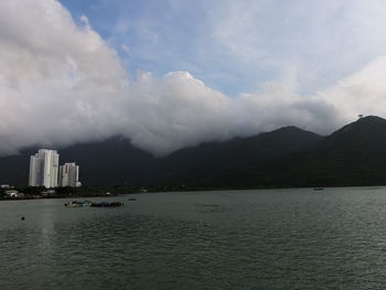 Scenic view of sea by city buildings against sky