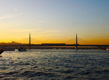 Bridge over calm river against sky during sunset