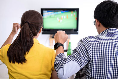 Rear view of man and woman watching tv