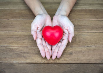 Directly above shot of woman holding heart shape on table