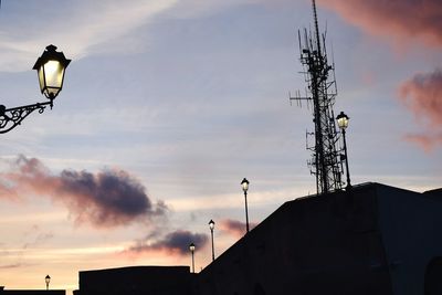 Low angle view of lighting equipment and communications tower against sky