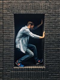 Young man standing on brick wall