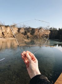 Close-up of hand holding ice against lake