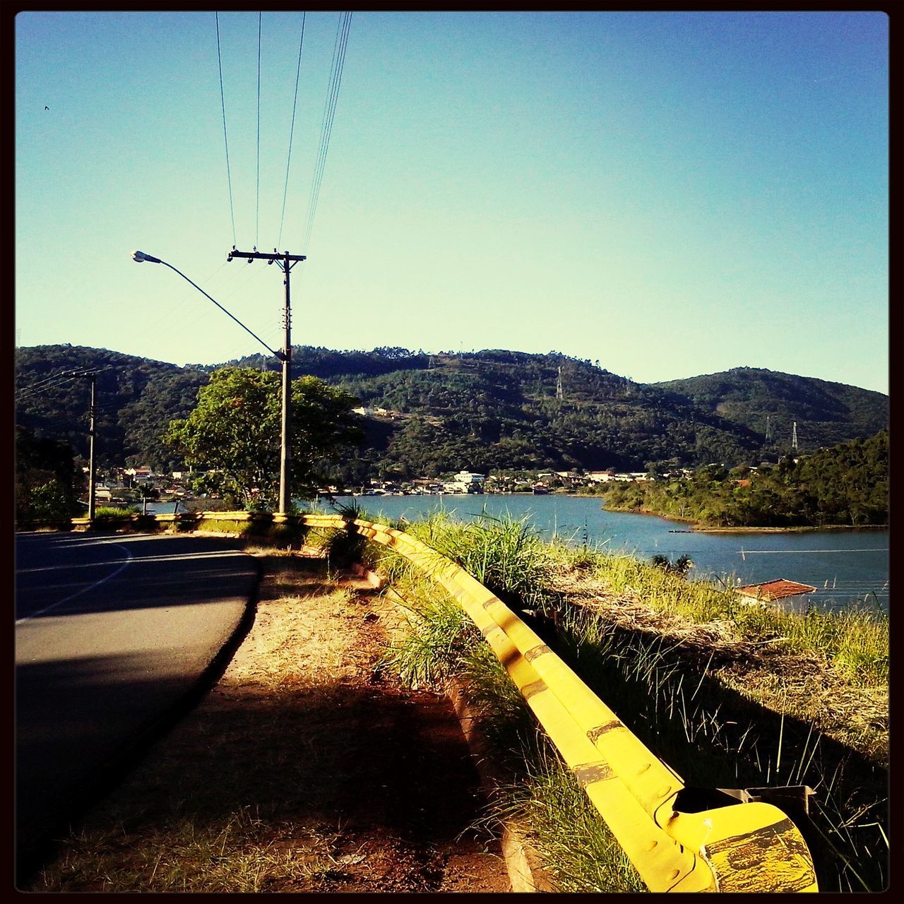 transfer print, clear sky, transportation, mountain, water, road, tranquil scene, tree, tranquility, auto post production filter, scenics, nature, beauty in nature, blue, mode of transport, landscape, sky, copy space, mountain range, car