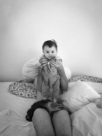 Portrait of cute baby sitting on bed at home