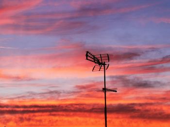 Low angle view of electricity pylon against sky during sunset