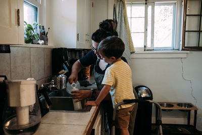 Mother and child working together at kitchen sink