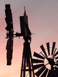 Silhouette cranes against sky during sunset