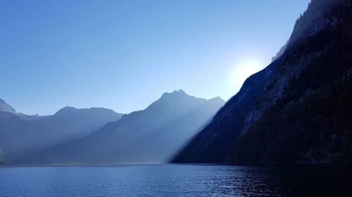 Scenic view of lake and mountains against clear blue sky