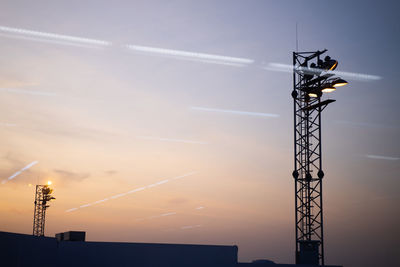 Low angle view of electricity pylon against sky during sunset