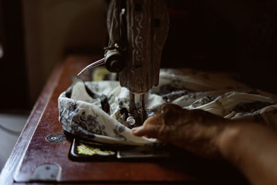 Cropped hand of woman using sewing machine at home