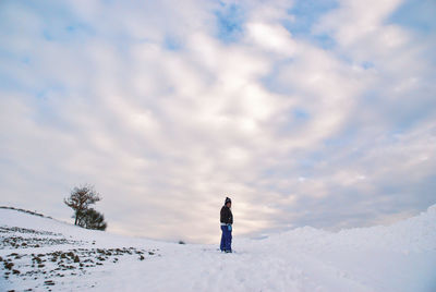 Full length of woman standing on snow covered landscape against sky