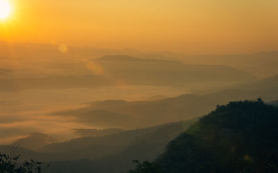 Scenic view of silhouette mountains against orange sky