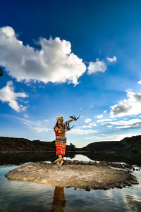 Woman standing on rock against sky