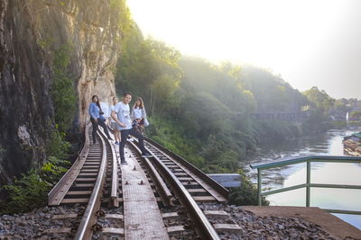 People on railroad tracks against trees