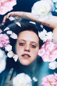 High angle portrait of woman with pink flowers in bathtub