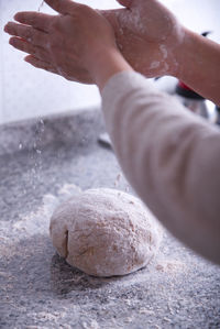 Woman's hands preparing homemade bread dough in a kitchen.