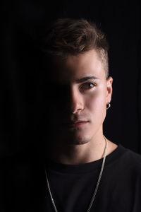 Portrait of teenage boy standing against black background