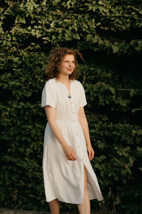 Portrait of young woman standing against plants