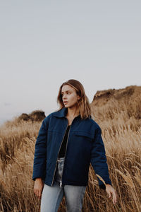 Young woman standing by plants against sky