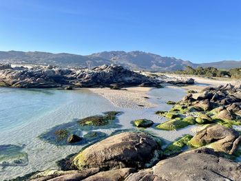 Scenic view of sea and mountains against clear sky