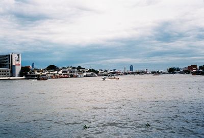 Sea by buildings against sky in city
