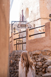 Rear view of woman standing against building