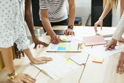 Close-up of colleagues working together at desk in office discussing papers