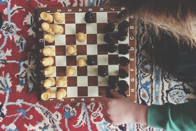 Cropped hand playing chess on bed