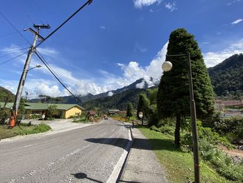 Road by trees against sky