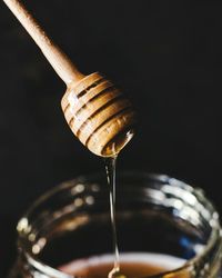 Close-up of dipped pouring honey in jar