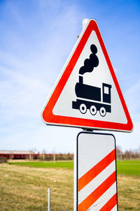 Close-up of railroad crossing sign against sky