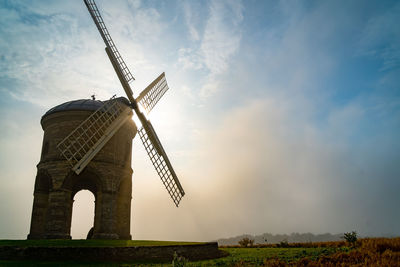 Low angle view of traditional windmill on field against sky