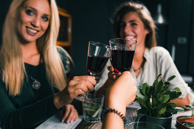 Cheerful female friends toasting wineglass at table in restaurant