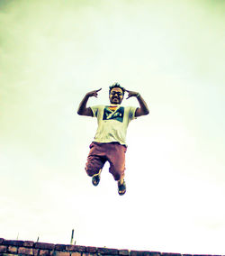 Low angle view of man jumping against sky