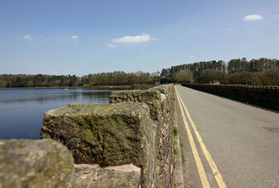 Road by lake against sky