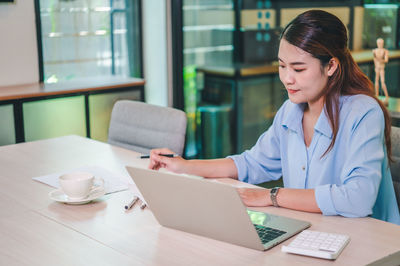 Portrait of young woman using laptop at table