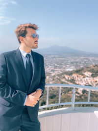 Man standing by railing against sky