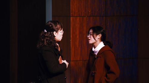 Side view of young woman standing against wall