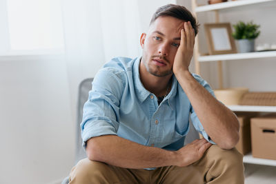 Portrait of young man sitting on sofa at home