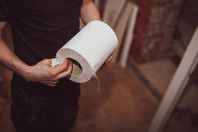 Caucasian male builder holds a paper towel in his hands.