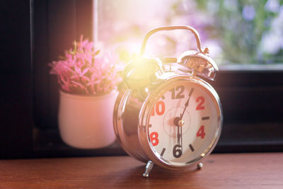 Close-up of pink clock on table at home