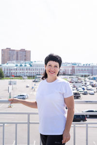 Portrait of smiling young woman standing against railing