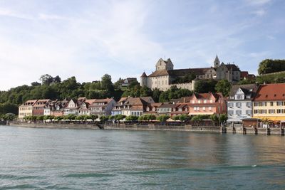 Buildings by river against sky